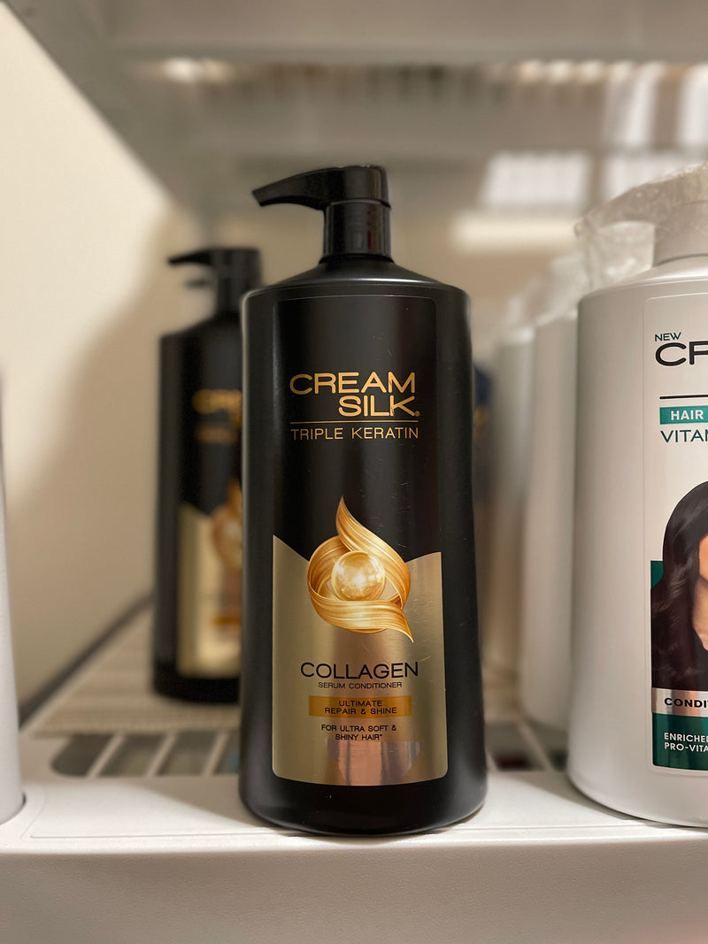 A bottle of Cream Silk Triple Keratin Rescue Conditioner with a pump dispenser, positioned on a shelf with other hair care products in the background.